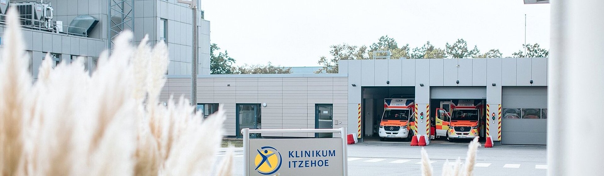 Hubschrauberlandeplatz und Rettungswagen-Liegendanfahrt, im Vordergrund Gräser und ein Klinikum Itzehoe-Schild.