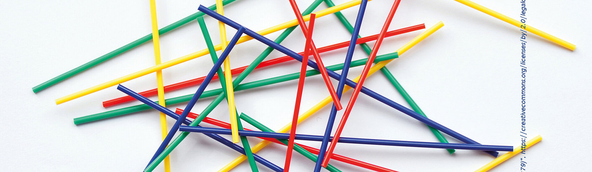 Dünne Stäbe in rot, grün, gelb und blau liegen kreuz und quer übereinander.