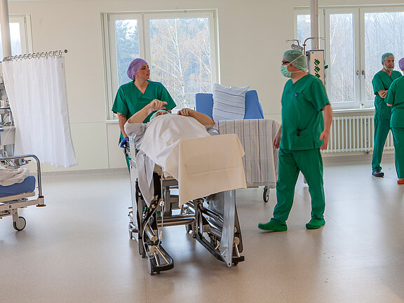 Patient wird vom OP-Team in den Aufwachraum gebracht.