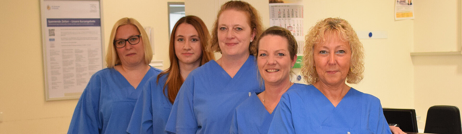 Fünf Pflegefachkräfte lächeln ins Bild. Fünf Pflegefachkräfte lächeln ins Bild.
