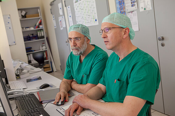 Zwei Operateure der Gefäßmedizin sehen sich Untersuchungsergebnisse am Monitor an