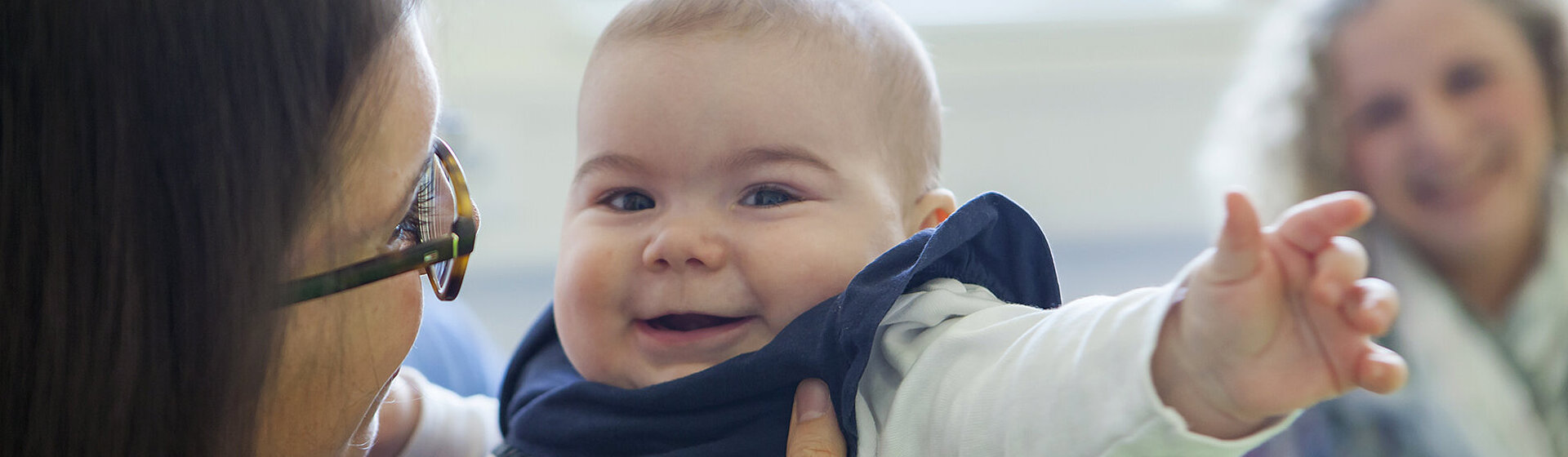 Mutter mit Baby im Arm in einer Therapiesituation mit Therapeutin.