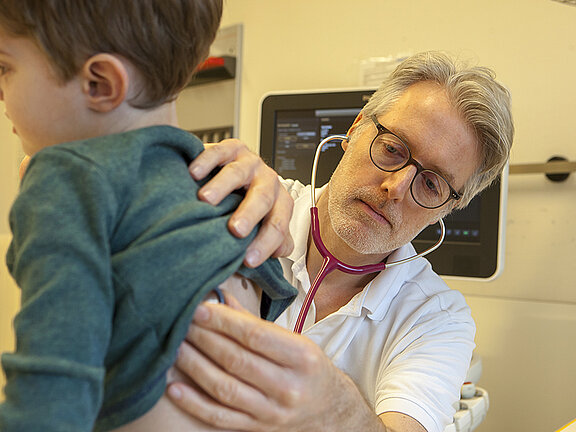 Chefarzt Dr. med. Georg Hillebrand horcht einen kleinen Patienten mit dem Stetoskop ab.