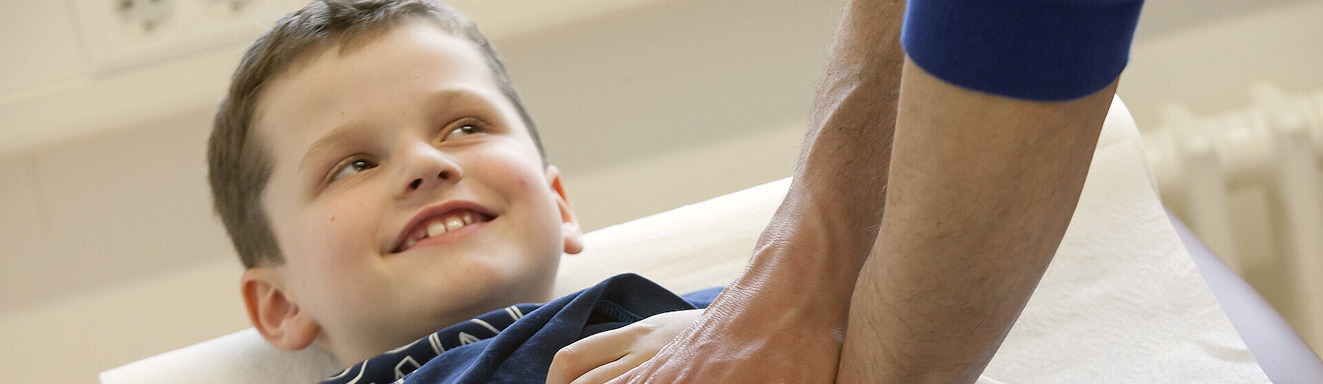 Ein Junge liegt auf einer Untersuchungsliege während ein Mediziner seinen Bauch abtastet. Ein Junge liegt auf einer Untersuchungsliege während ein Mediziner seinen Bauch abtastet.