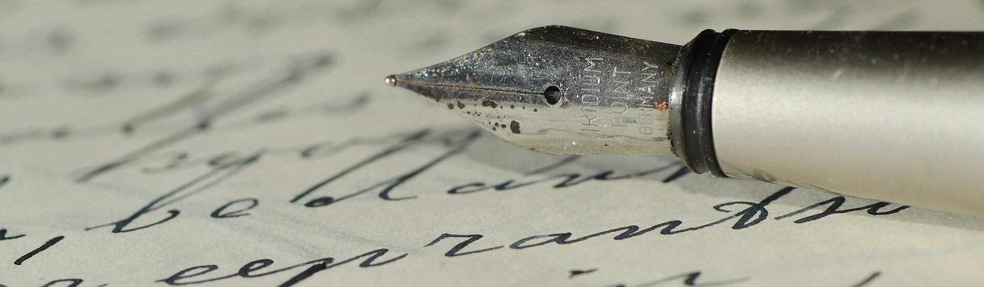 Handschriftlich beschriebenes Blatt Papier und die Spitze eines Füllfederhalters