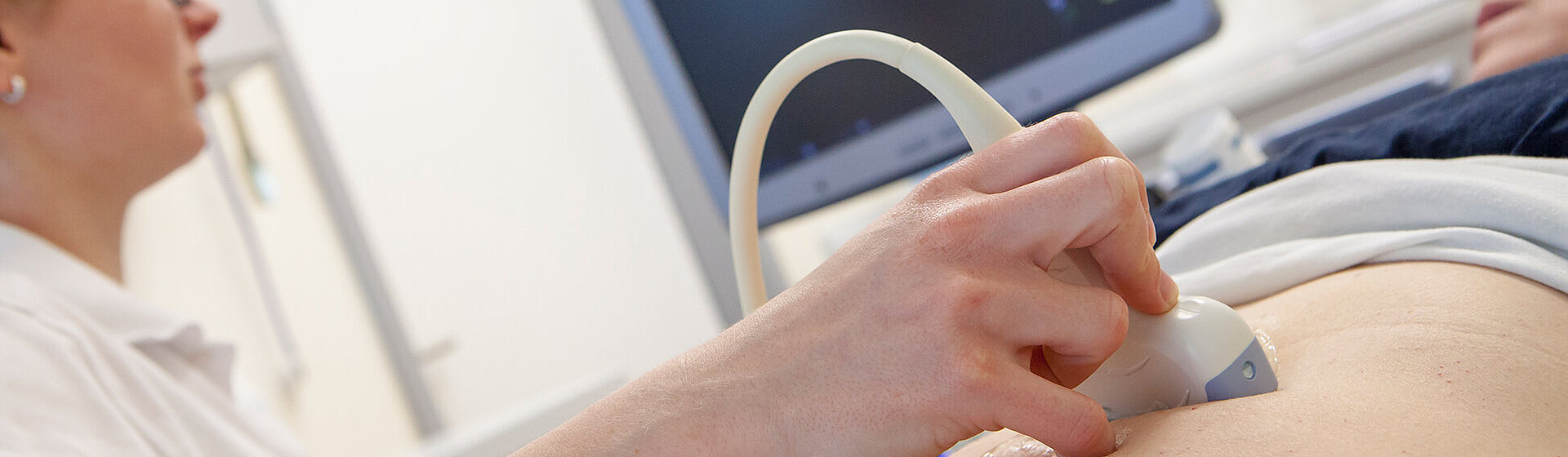 Medizinische Fachkraft hält das Sonografiegerät auf den Bauch der Patientin. Medizinische Fachkraft hält das Sonografiegerät auf den Bauch der Patientin.