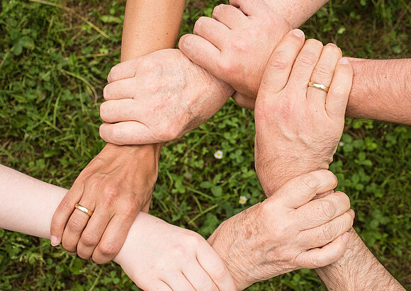 Interessenvertretung Hände greifen jeweils das nächste Handgelenk im Kreis, Ansicht von oben