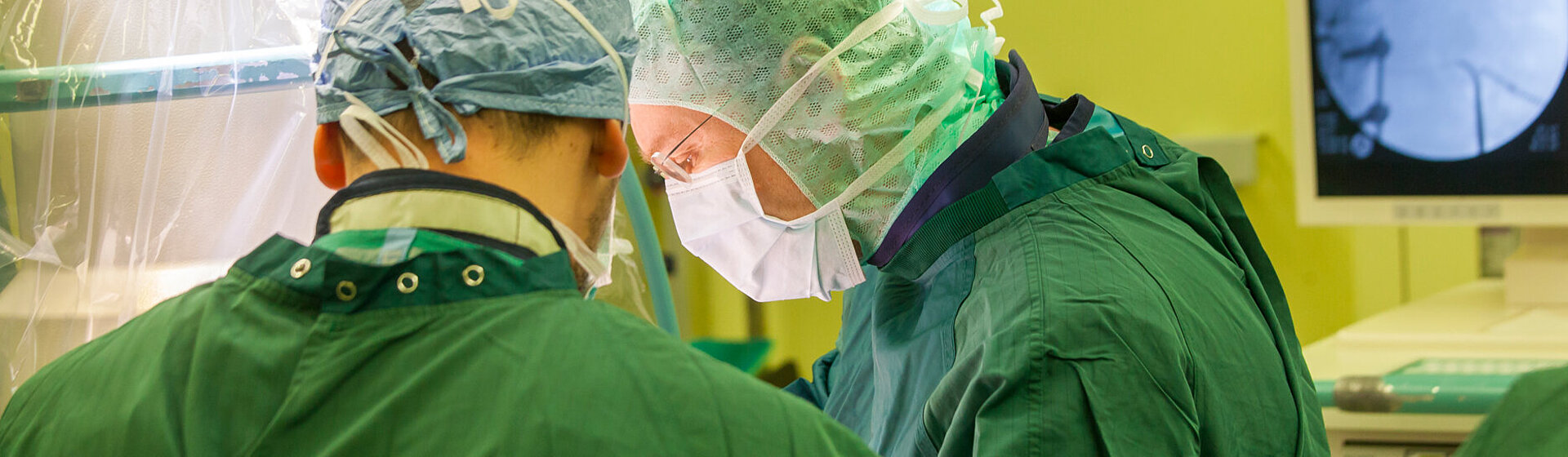 Zwei Operateure in OP-Kleidung im OP-Saal sind konzentriert auf die Operation.