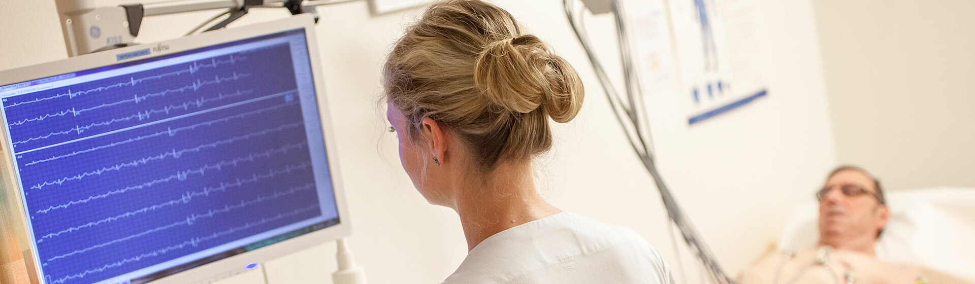 Patient liegt auf Untersuchungsliege und eine Medizinerin schaut auf dem Monitor. Patient liegt auf Untersuchungsliege und eine Medizinerin schaut auf dem Monitor.