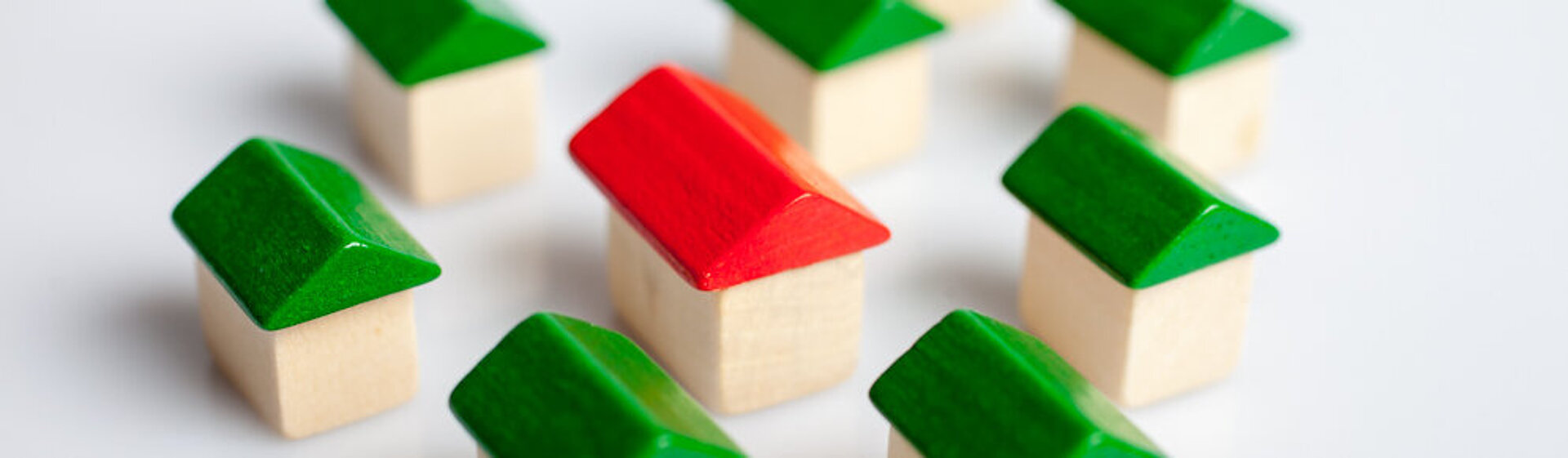 Spiel-Holzhäuser mit grünen Dächern, in der Mitte eines mit einem roten Dach Spiel-Holzhäuser mit grünen Dächern, in der Mitte eines mit einem roten Dach