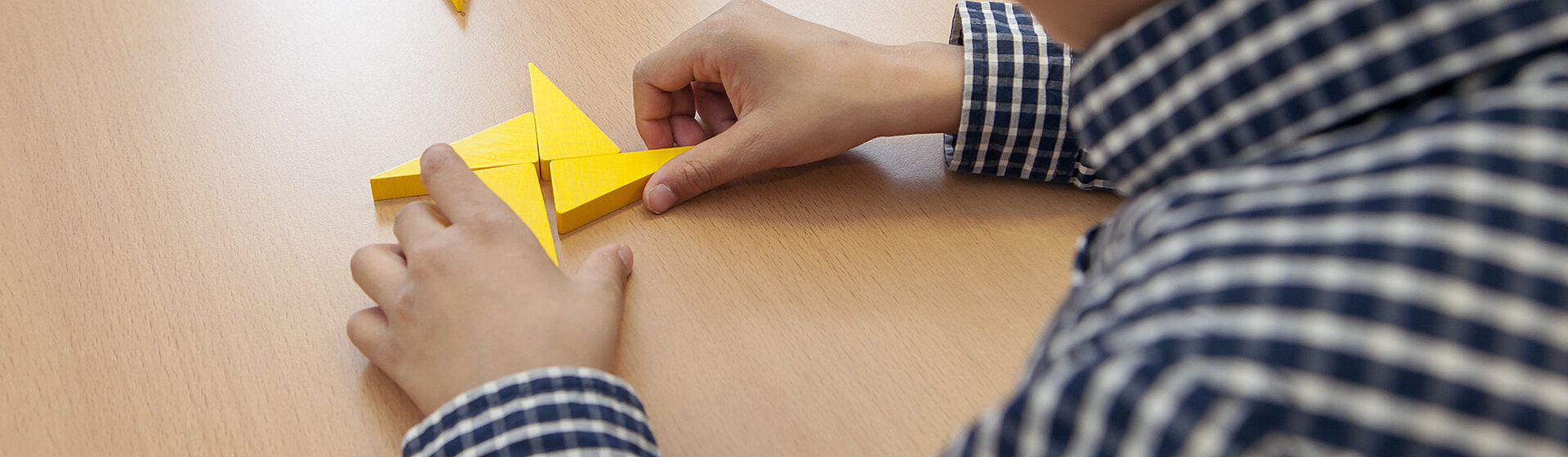 Ein Junge sitzt am Tisch und puzzelt ein Holz-Puzzle. Ein Junge sitzt am Tisch und puzzelt ein Holz-Puzzle.