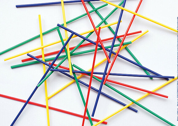 Case Management/ Sozialdienst/Familiale Pflege Dünne Stäbe in rot, grün, gelb und blau liegen kreuz und quer übereinander.