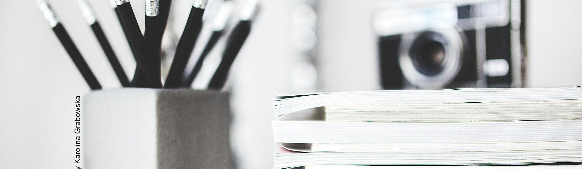 Leicht verschwommene Aufnahme von Bleistiften, einer Kamera und Akten.