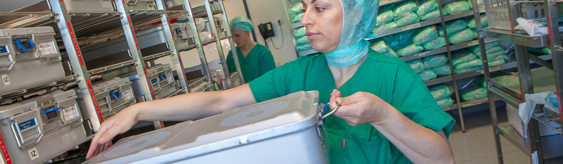 Operationstechnische Assistentin (OTA) nimmt einen Sterilgutcontainer mit OP-Instrumenten aus dem Regallager. Operationstechnische Assistentin (OTA) nimmt einen Sterilgutcontainer mit OP-Instrumenten aus dem Regallager.