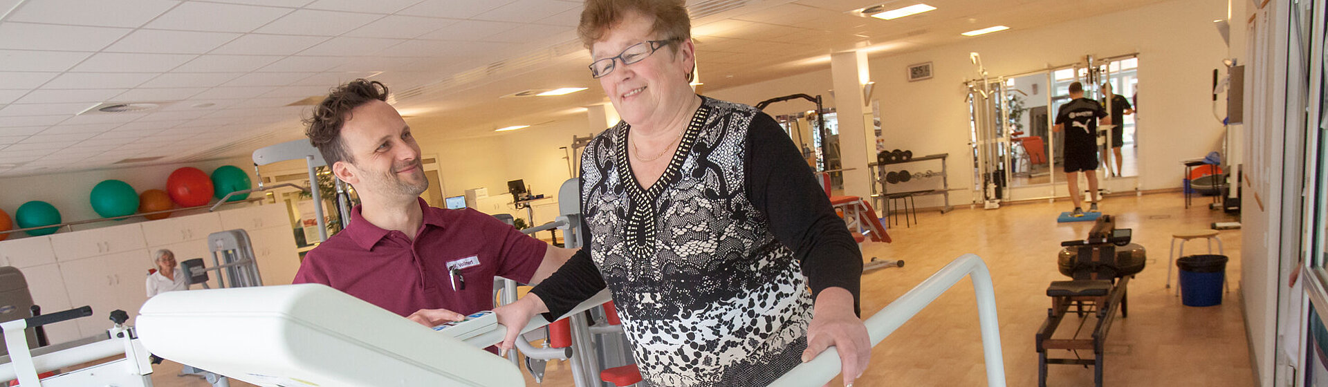 Ein Physiotherapeut leitet eine Patientin auf dem Laufband im MediFit an.