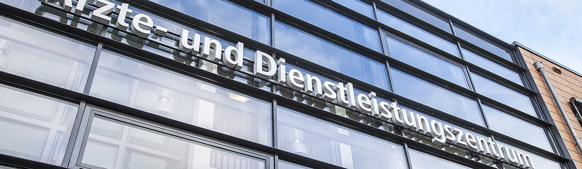 Glasfront oberhalb des Einganges mit Schriftzug Ärzte- und Dienstleistungszentrum