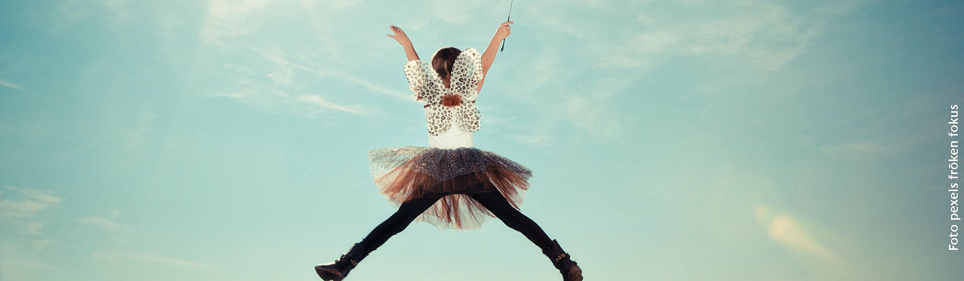 Ein Mädchen in einem Elfenkostüm macht einen Luftsprung.