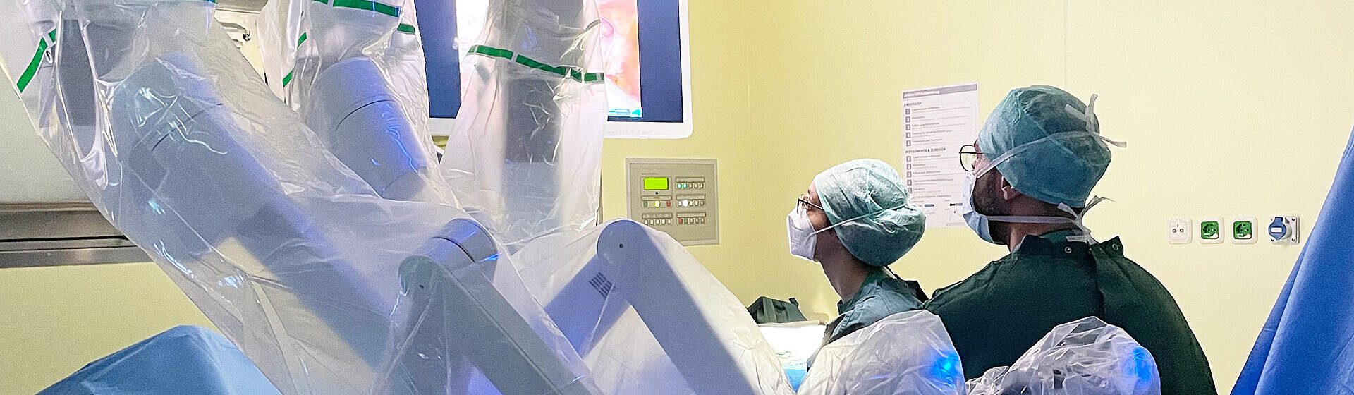 Eine weibliche und eine männliche Person vom medizinischen Fachpersonal arbeiten am OP-Roboter Da Vinci.