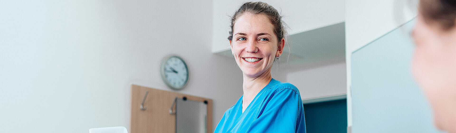 Pflegefachkraft lächelt PatientIn mit hochgelagertem Bein an. Pflegefachkraft lächelt PatientIn mit hochgelagertem Bein an.