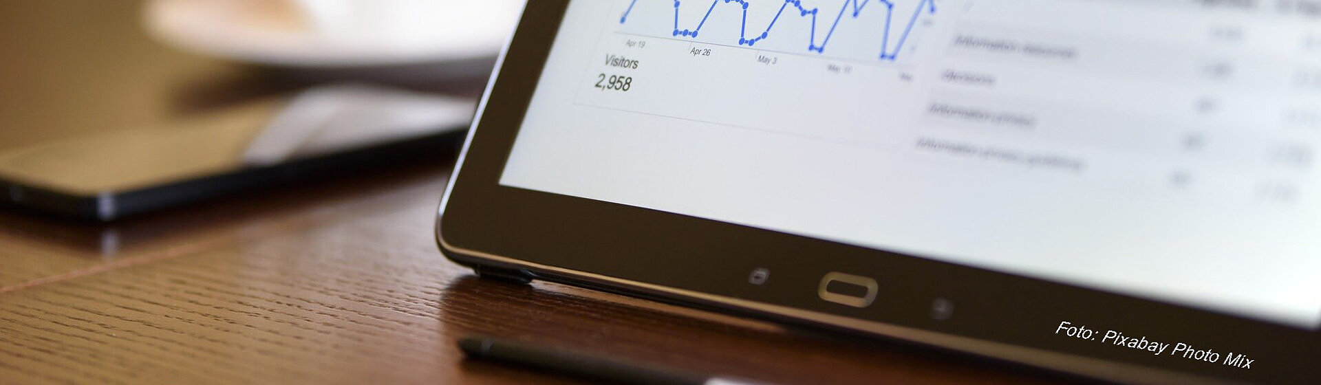 Tablett, Handy und eine Tasse stehen auf einem Tisch. Tablett, Handy und eine Tasse stehen auf einem Tisch.