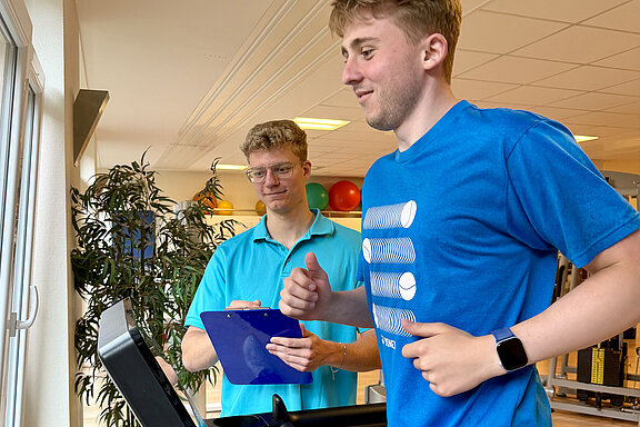Trainierende Person auf Laufband wird von einem MediFit-Mitarbeitenden betreut.