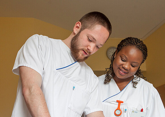 Pflege Zwei PflegerInnen am PatientInnenbett