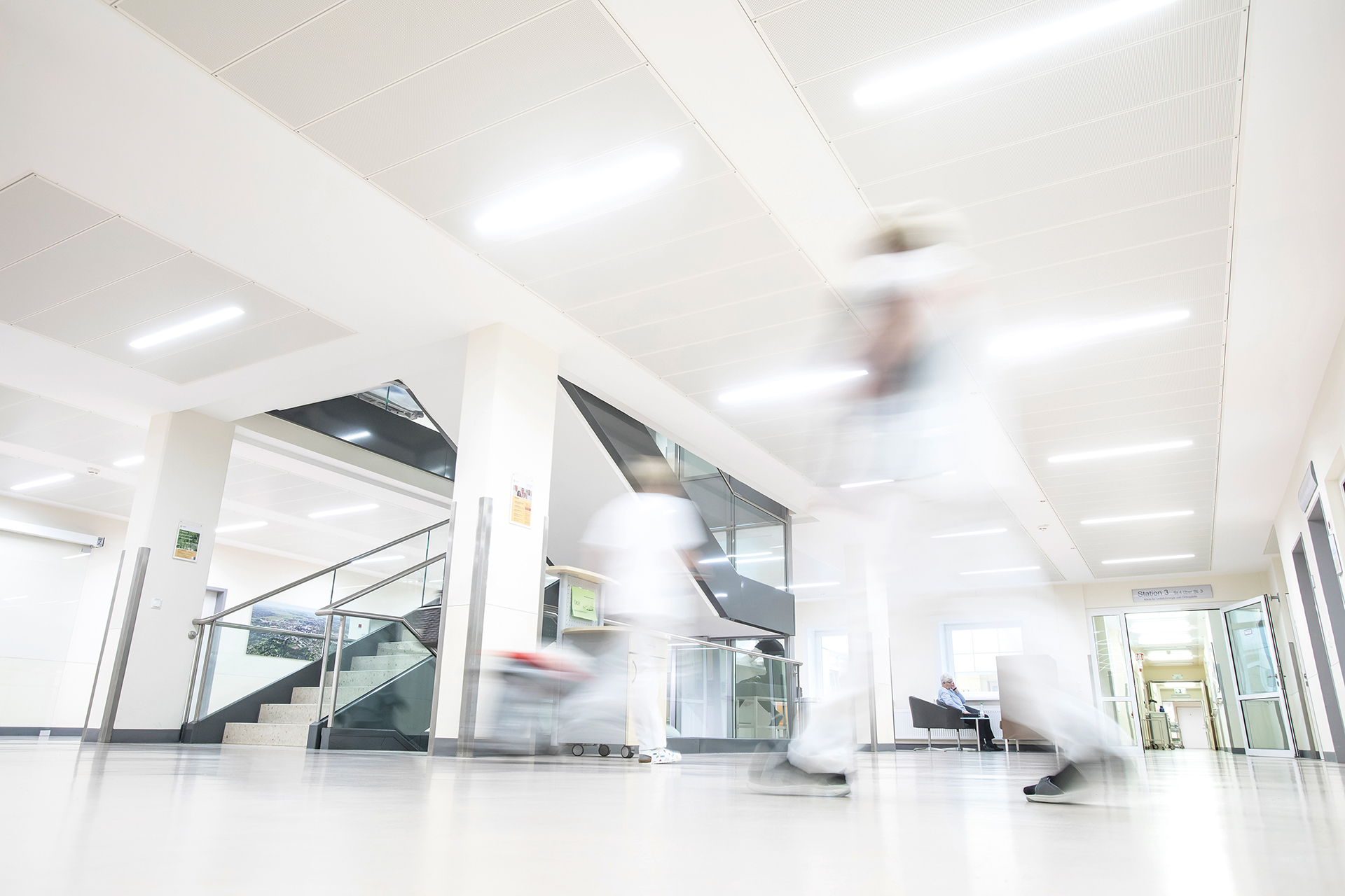 Flur im Klinikum Itzehoe mit Treppenhaus und Menschen, die sich in der Szenerie bewegen.