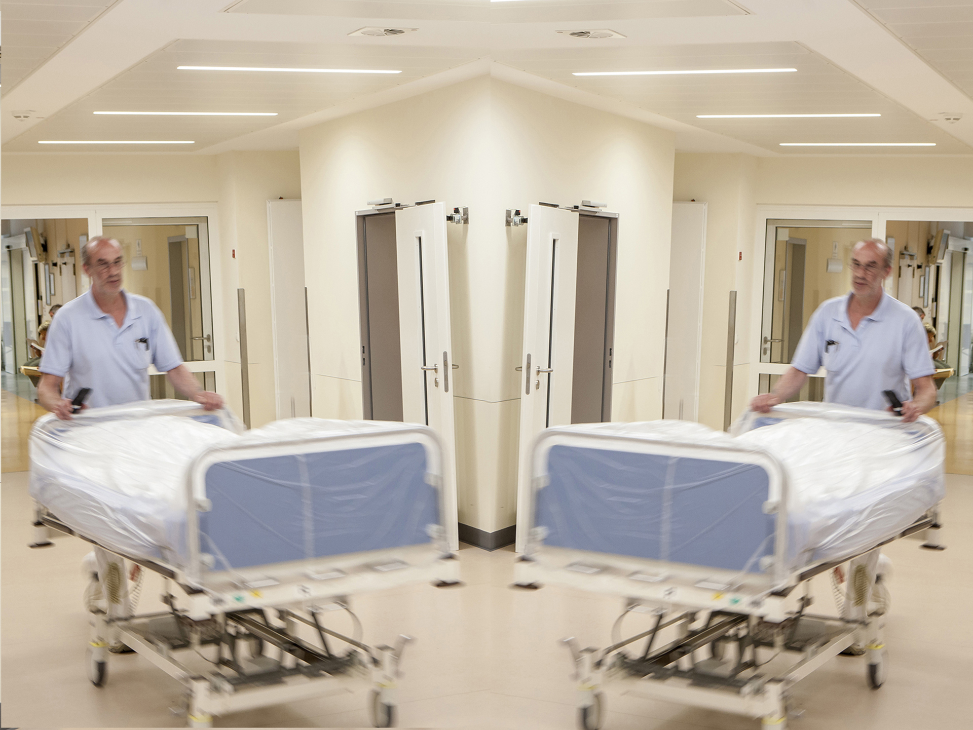 Ein Mitarbeiter des Transportdienstes schiebt ein leeres Bett. Ein Mitarbeiter des Transportdienstes schiebt ein leeres Bett.